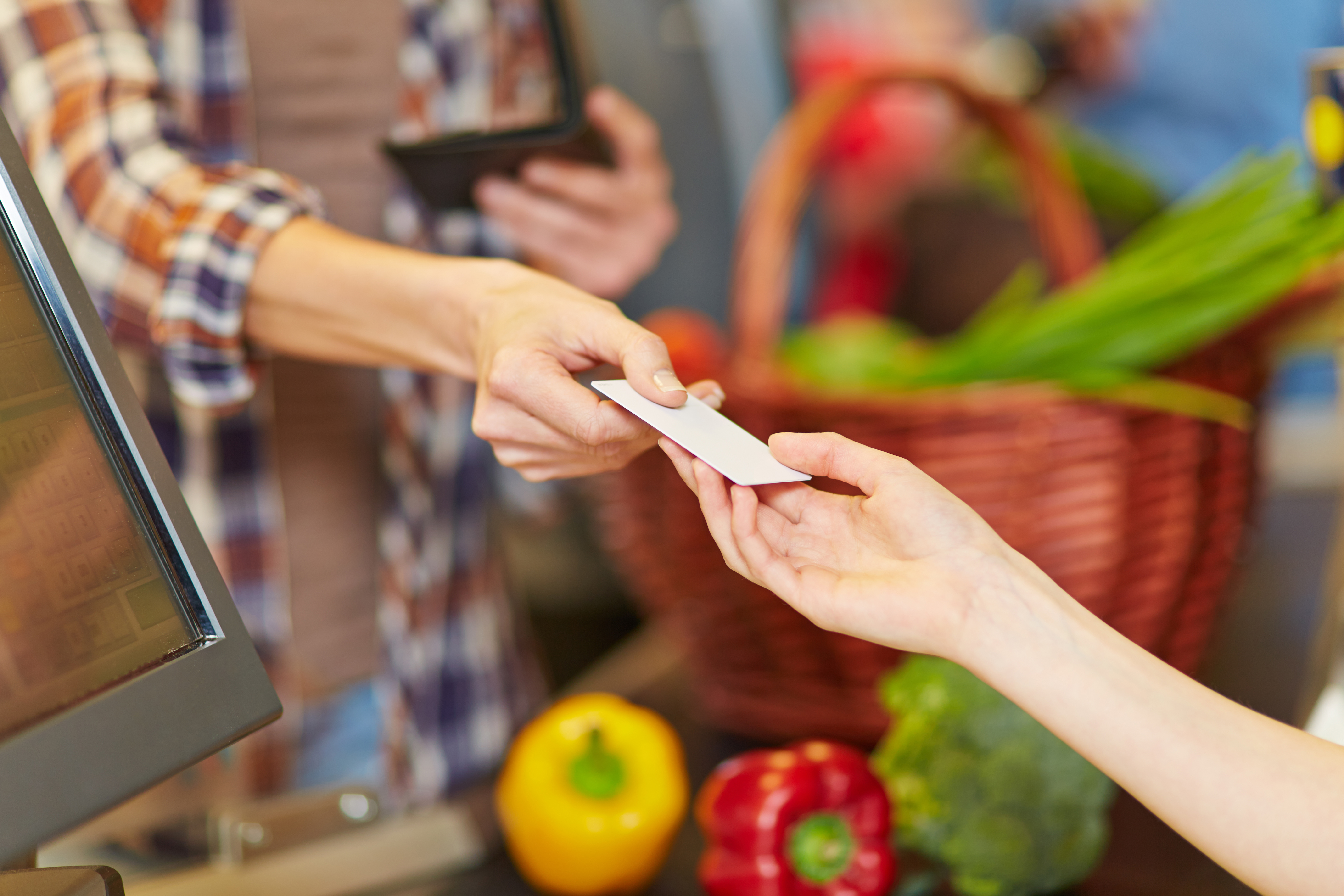 woman handing a grocery clerk a credit card